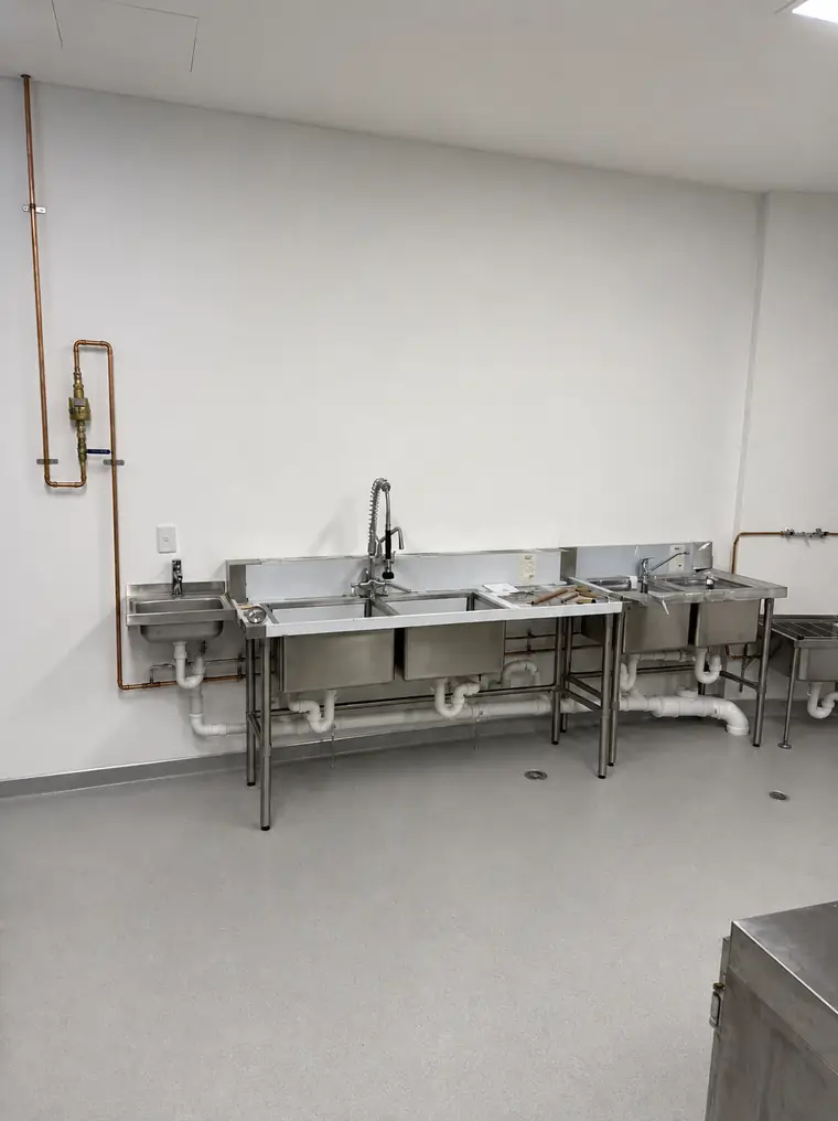 Commercial kitchen wash-up area with stainless steel sink plumbing